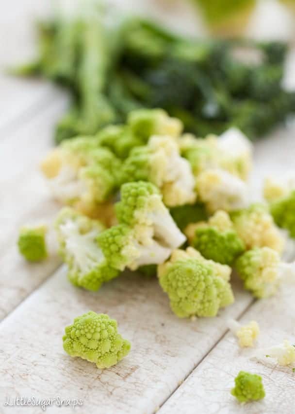 Green cauliflower (romanesco) broken into florets on a painted wooden table