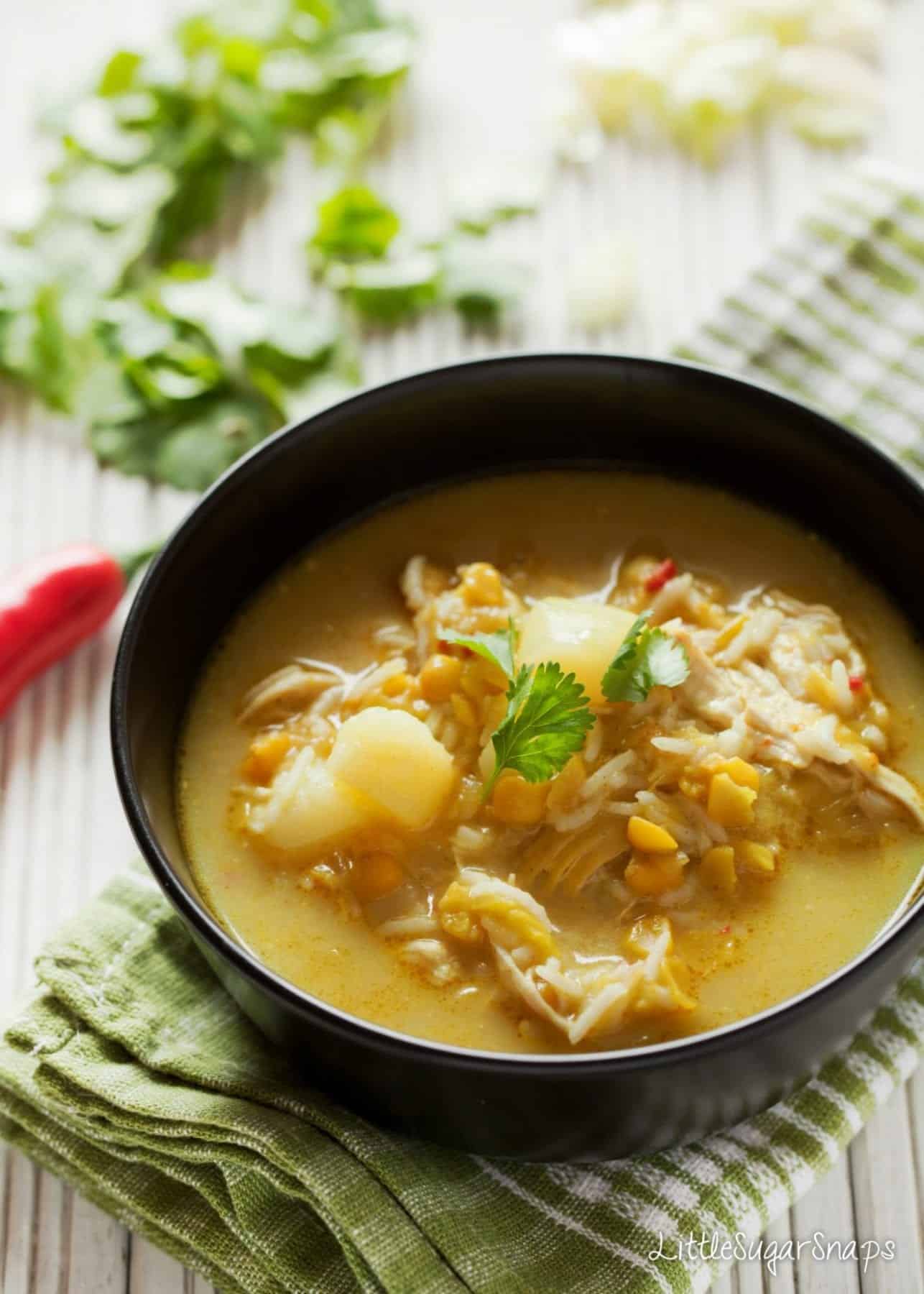 Spiced split pea Soup in a black bowl with chicken, potatoes and rice.