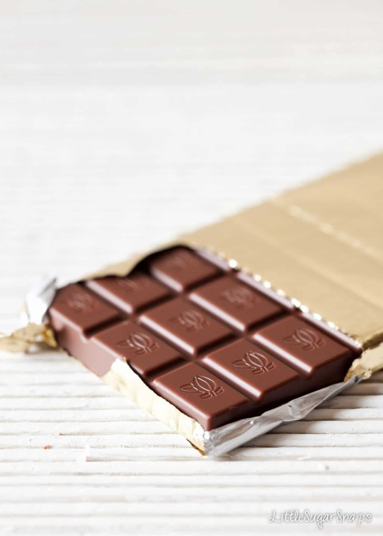 Milk chocolate bar wrapped in gold foil with the end squares exposed