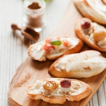 A platter of mixed taleggio crostini topped with roasted grapes, apple and parma ham