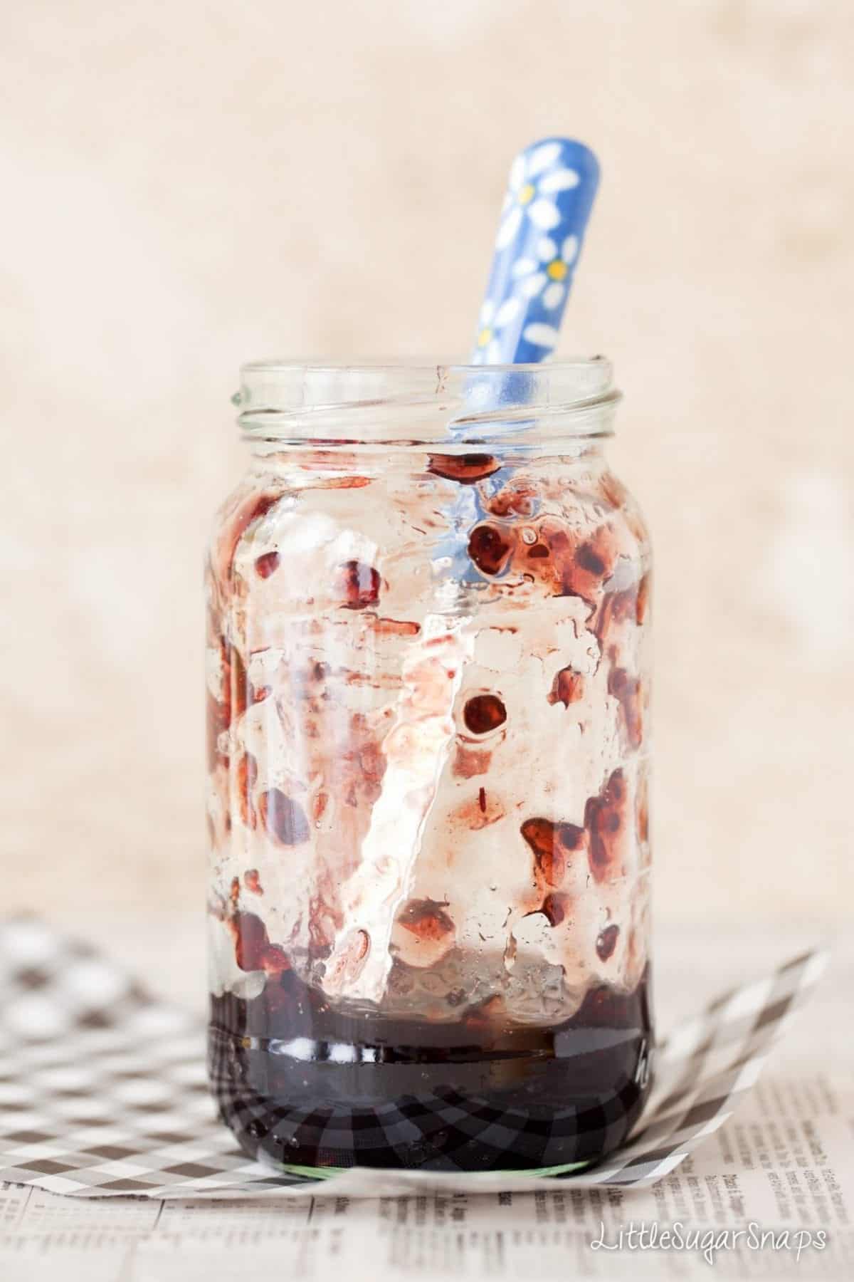 a jar of blackcurrant jam with a knife in it