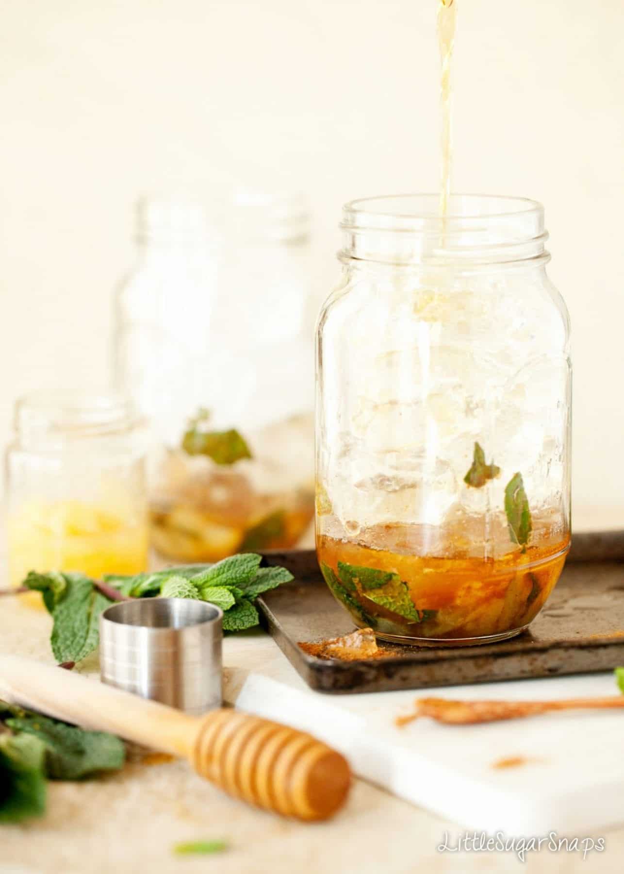 Pouring pineapple juice into muddled ingredients for a cocktail