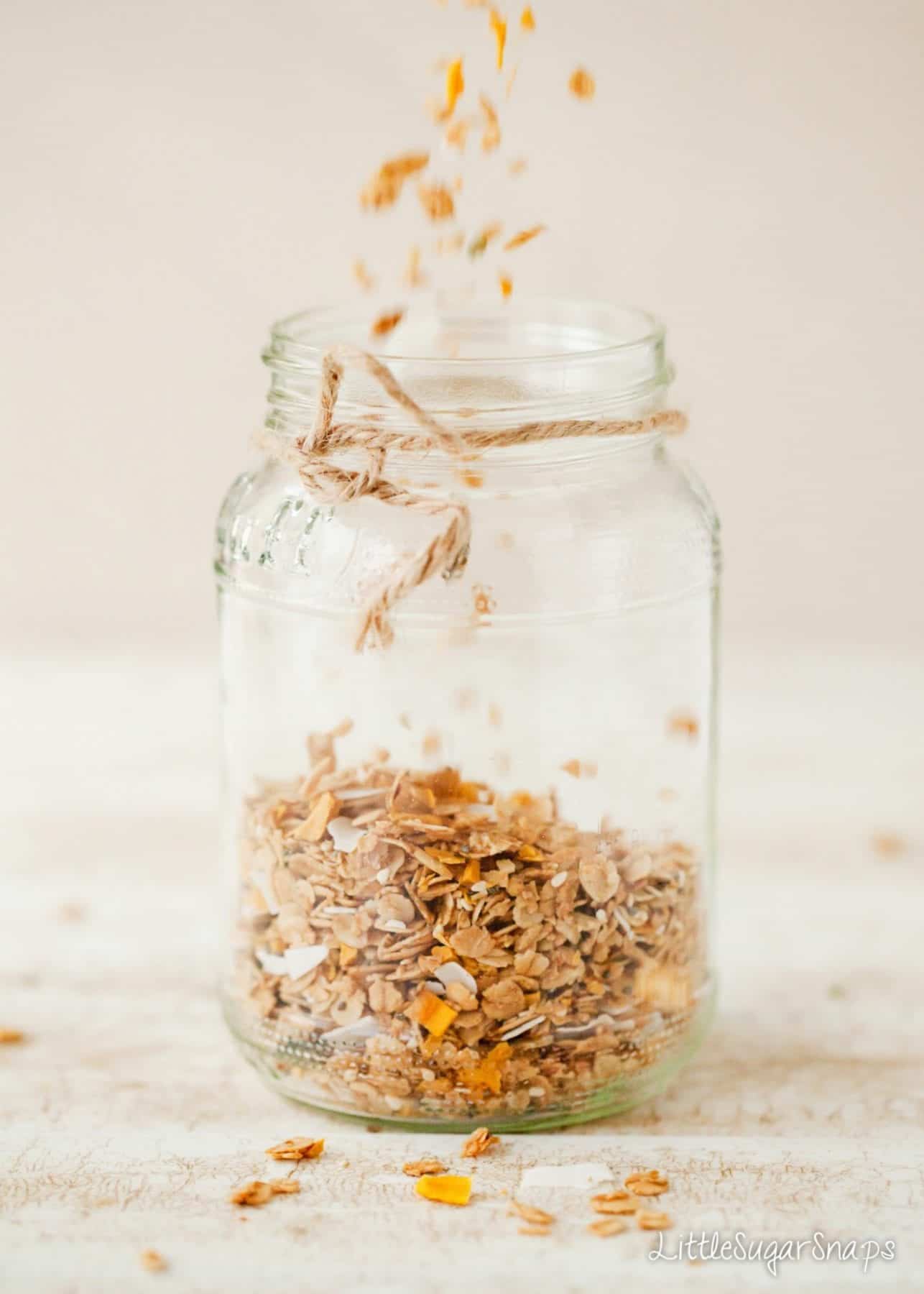 Homemade Granola being poured into a glass jar for storage