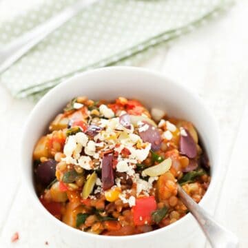 A bowl of lentil and olive stew topped with feta cheese, olives and chilli flakes