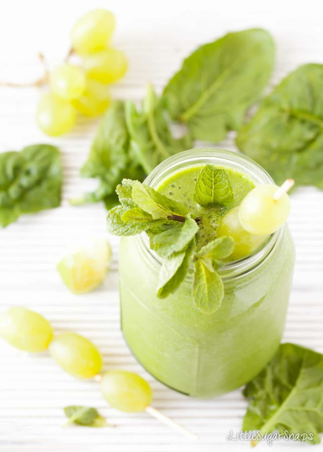 Green grape smoothie in a jam jar with grapes on a skewer and mint