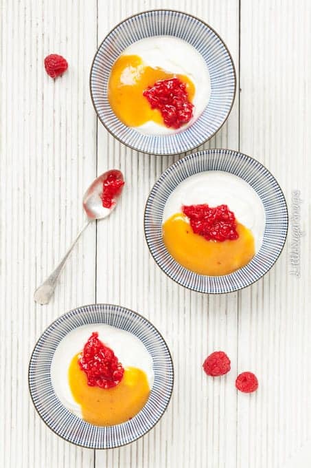 Yoghurt in bowls with peach puree and crushed raspberries