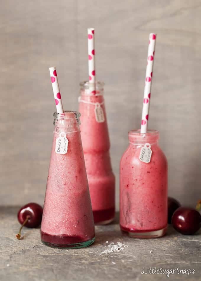 Three bottles containing Cherry Smoothie each with a paper straw in them