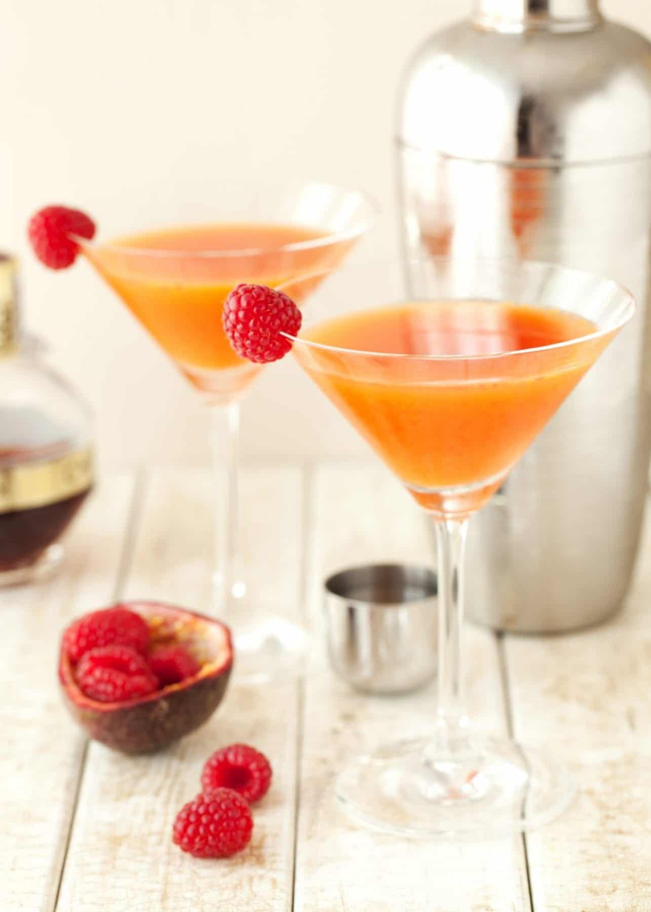 Two passionfruit and raspberry cocktails in martini glasses