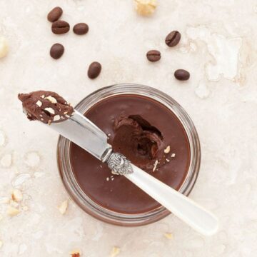 Over head view of a jar of Caffè Mocha chocolate spread with an ornate knife resting across the top. The knife has a scoop of the chocolate spread on it