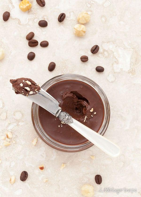 Open jar of chocolate spread with coffee and nuts
