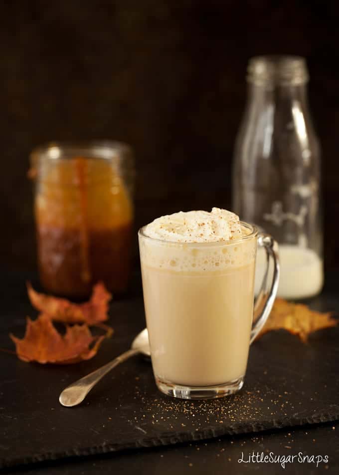 A glass mug of drinking caramel - topped with cream and ground spice. 