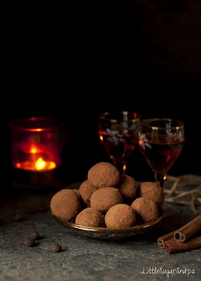 A plate of Chocolate Truffles with glasses of liqueur behind