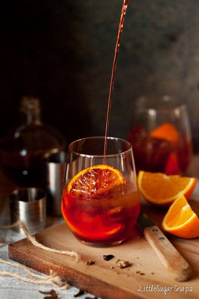 Pouring a negroni cocktail into a glass  