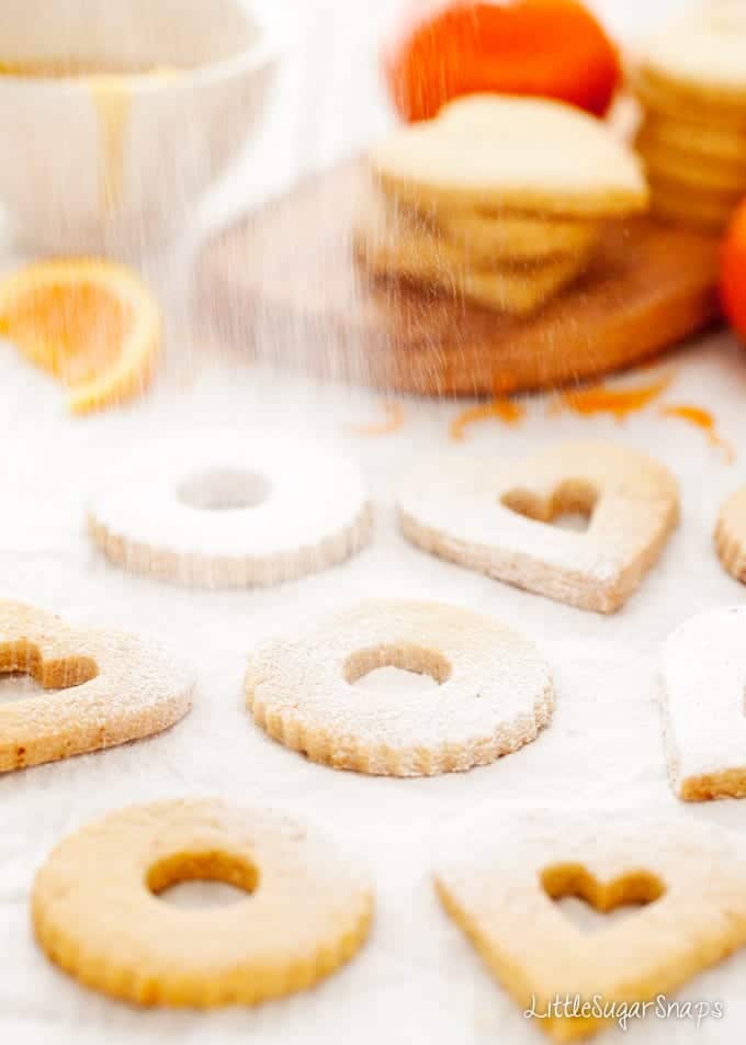 Heart and circle cut out cookies being dredged with icing sugar