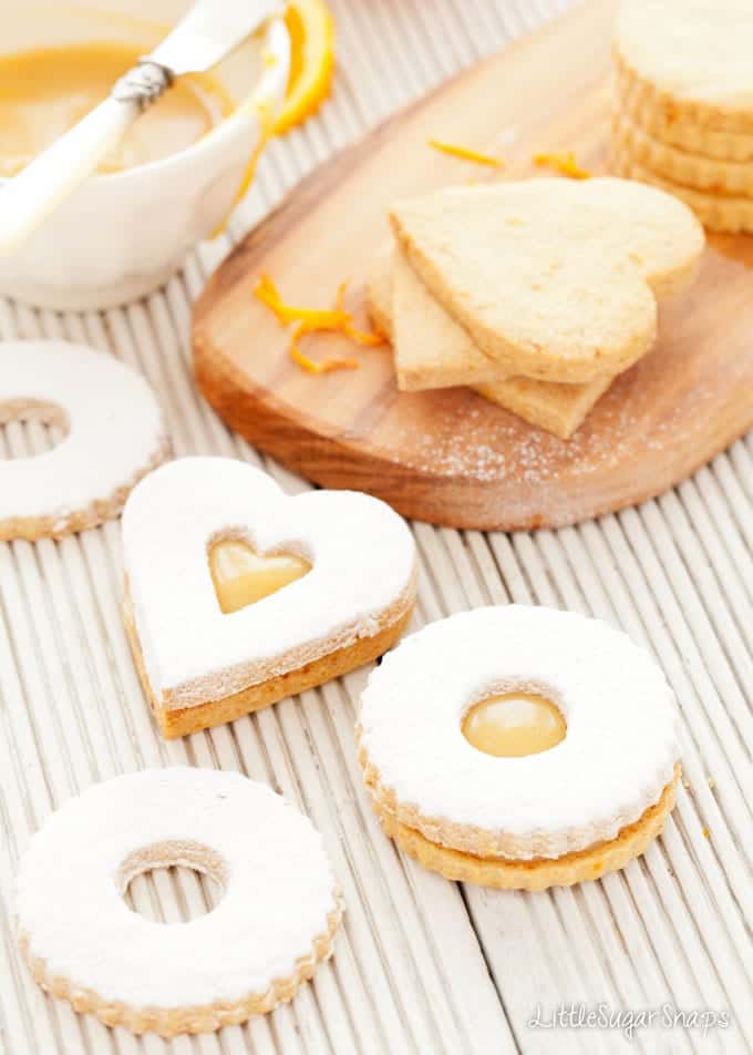 Linzer Cookies being sandwiched together with orange caramel spread