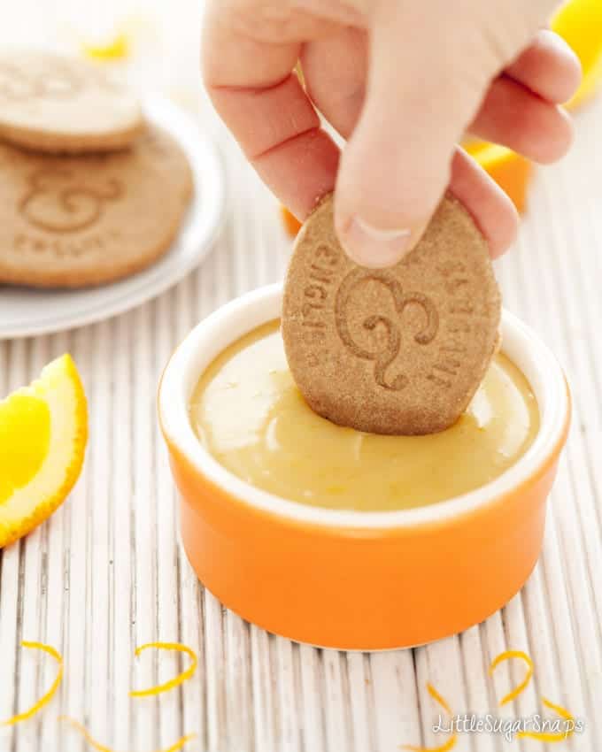 Dipping a biscuit into a pot of Orange Caramel Spread