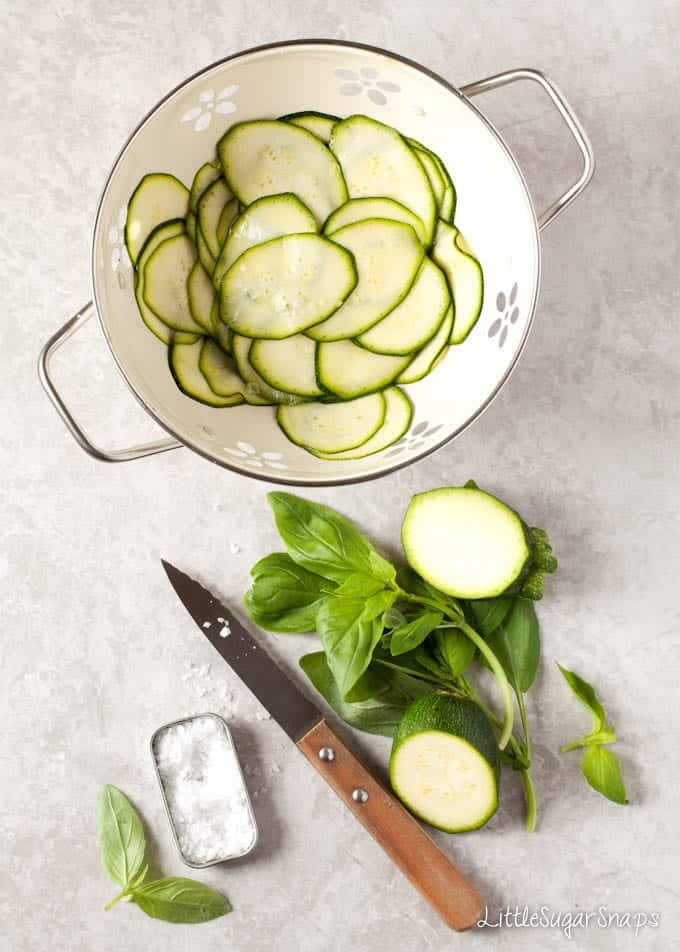 Sliced courgette in a colander being salted