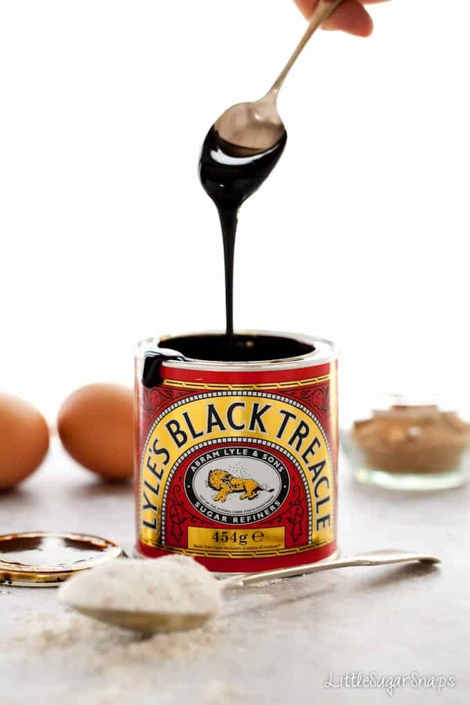 Black treacle dropping off a spoon back into its tin.