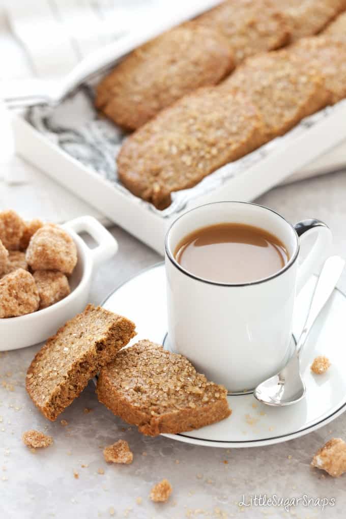 A white coffee with a snapped in half ginger biscuit