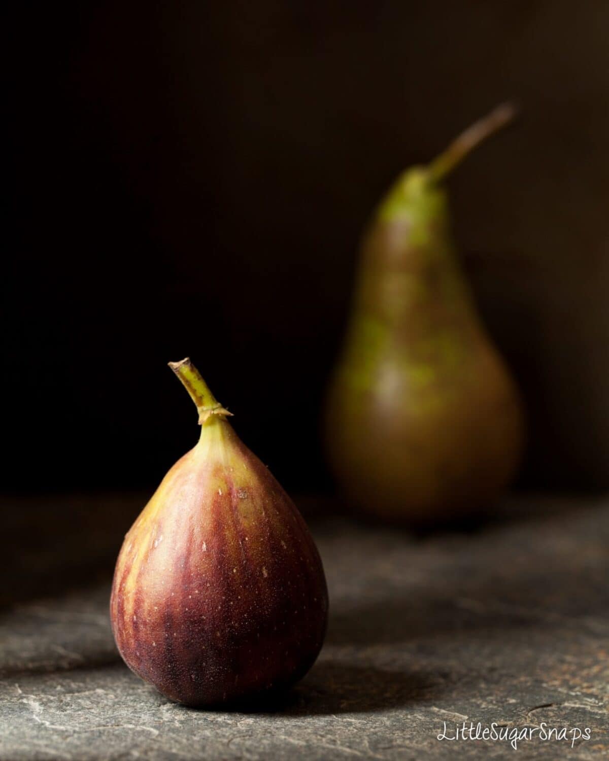 A fresh fig with a pear in the background