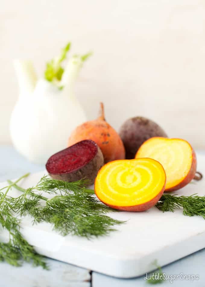 Golden and red beetroot cut open on a chopping board with fresh dill alongside