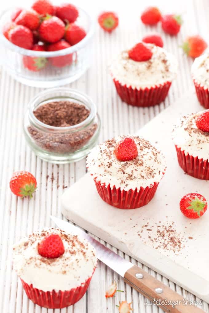 Red Velvet Cupcakes topped with frosting, strawberries and grated chocolate
