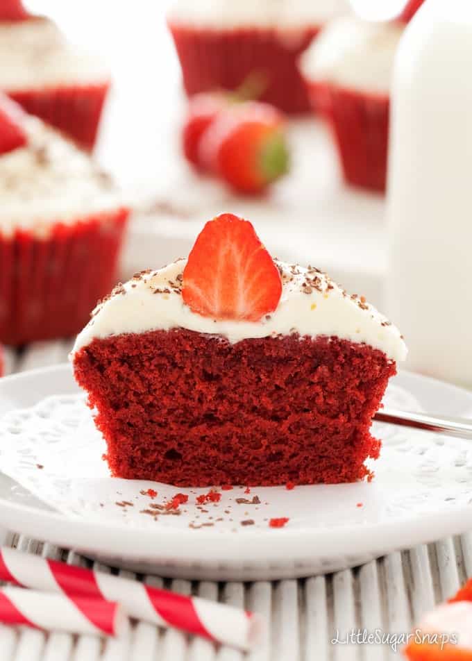 A Red Velvet Cupcake cut in half. With buttercream frosting and a strawberry garnish