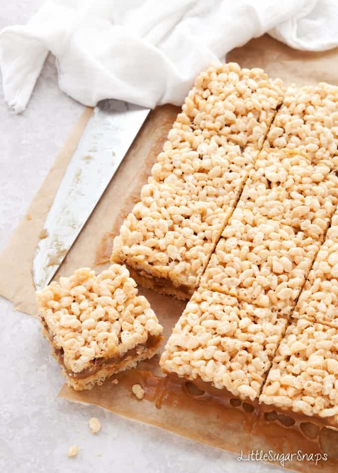 Salted Caramel rice Krispie Treats being cut into squares in parchment