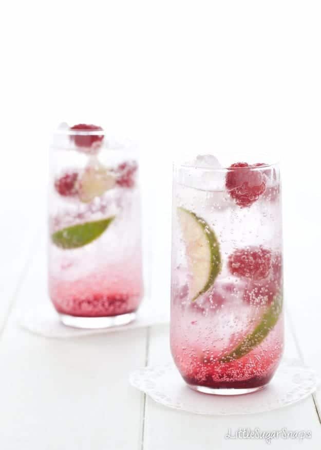 Hibiscus Raspberry Soda drinks with lime and raspberry garnish