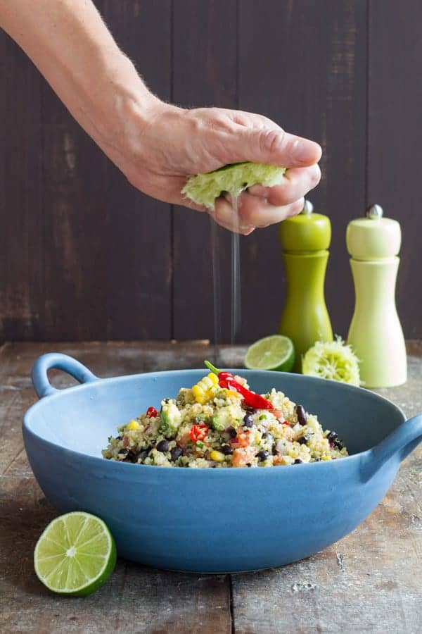 person squeezing lime juice over Mexican Quinoa Salad