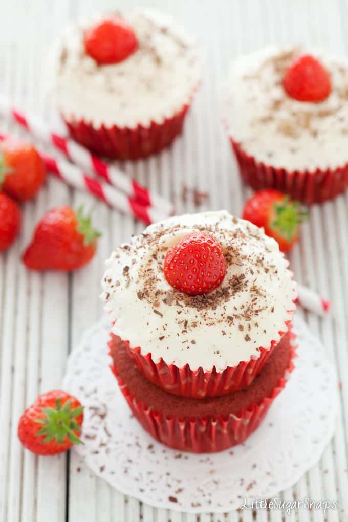 Red velvet cupcakes topped with strawberries and grated chocolate