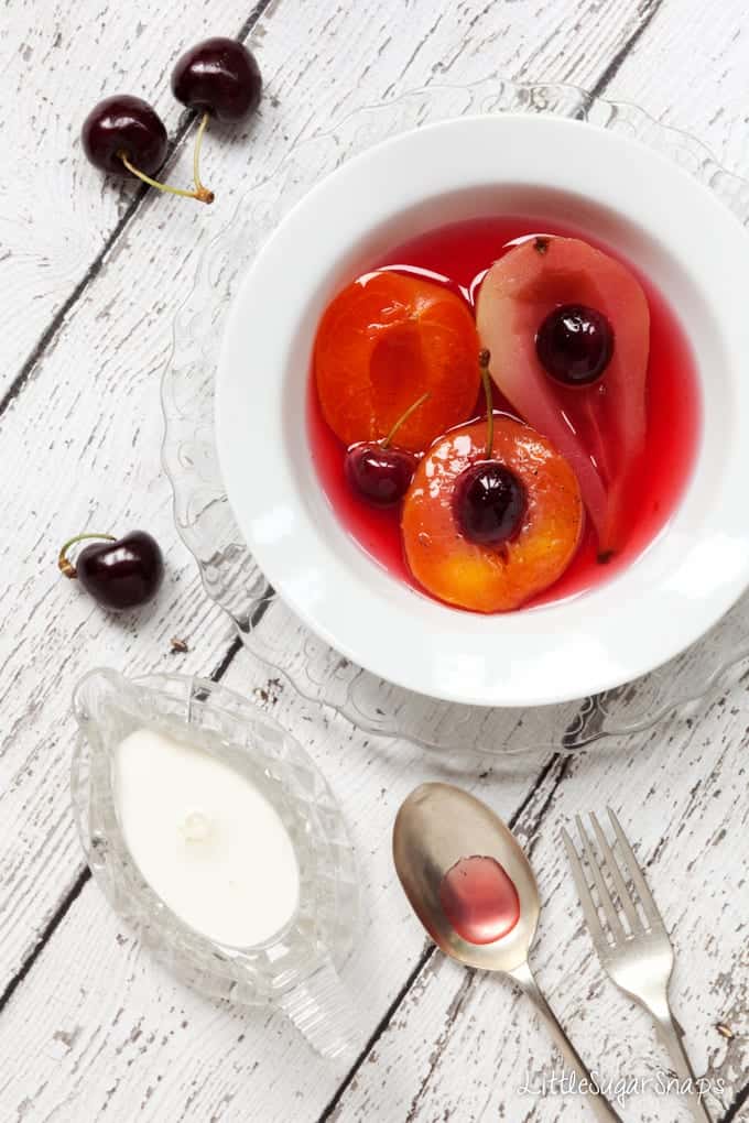 A bowl of Poached Fruit including pear, peach and cherries