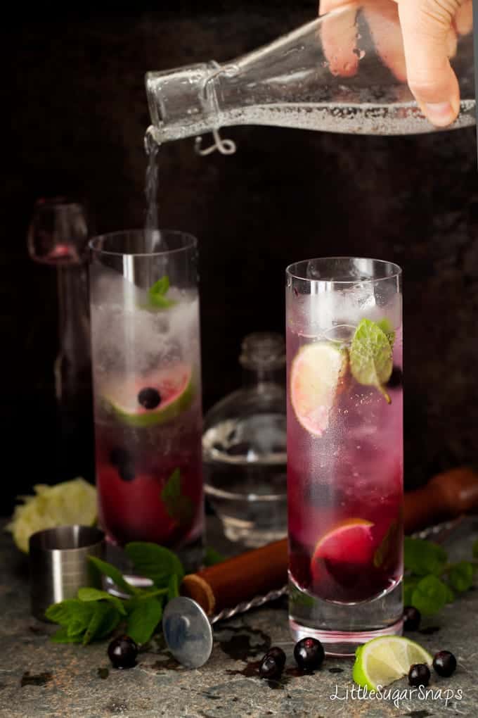 Blackcurrant Mojito cocktails in tall slim glasses with lime and mint 