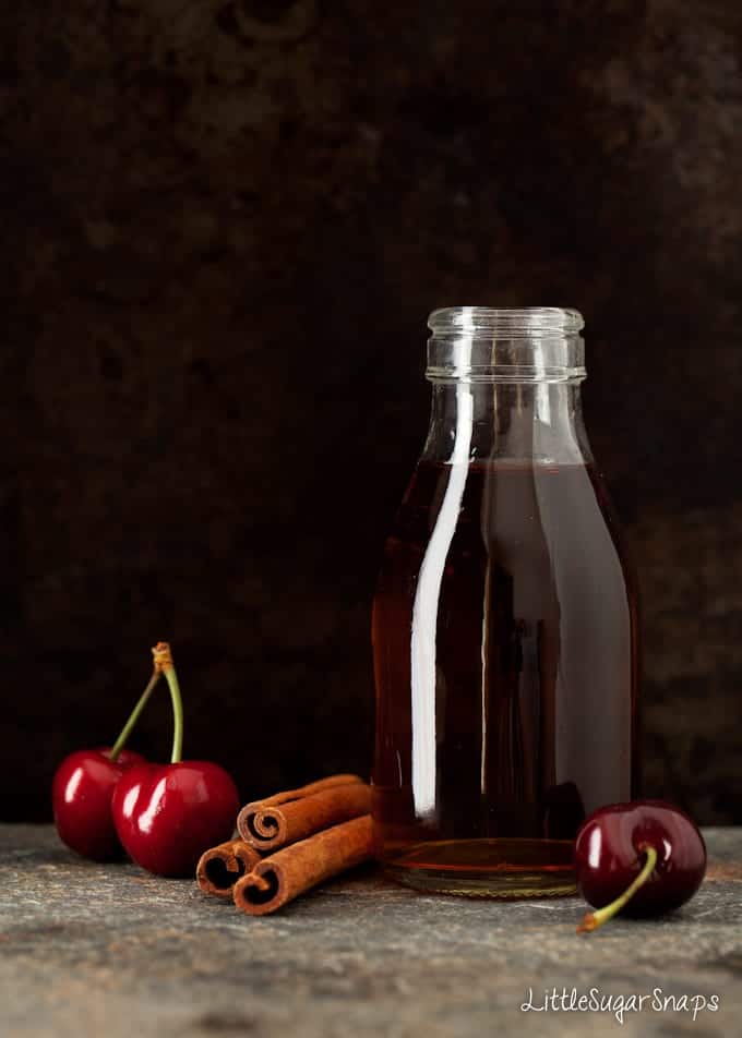 cherries, bourbon and cinnamon sitting on a worktop