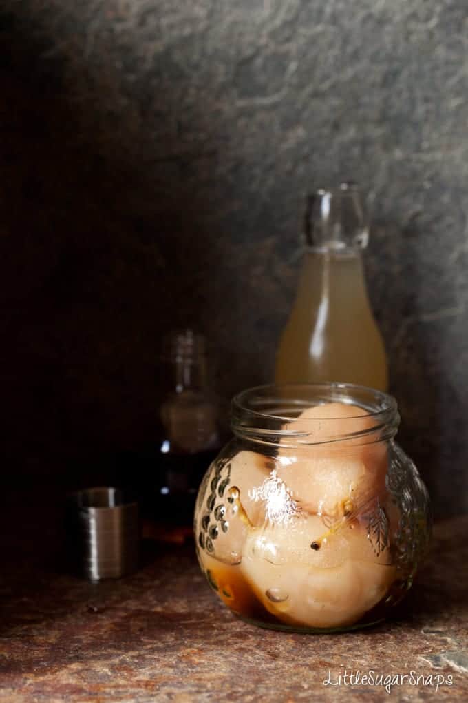 Poached pears in a jar with Amaretto poured in - process shot