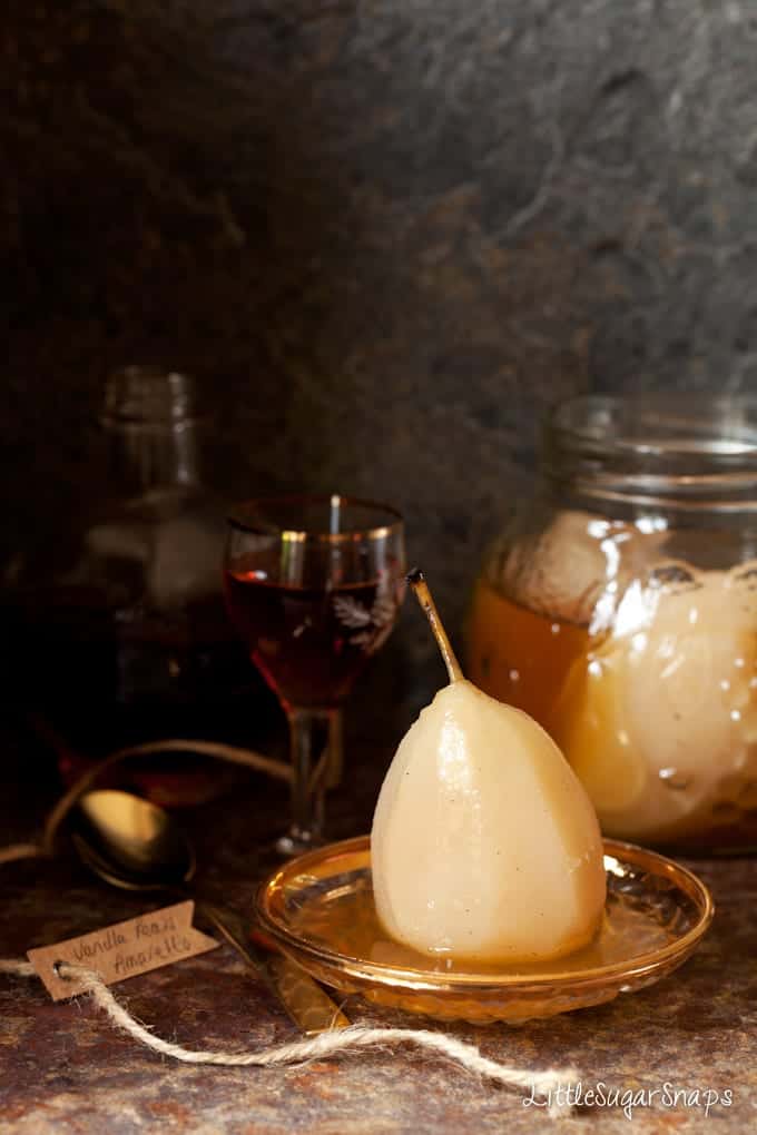 A poached pear in Amaretto syrup on a small plate