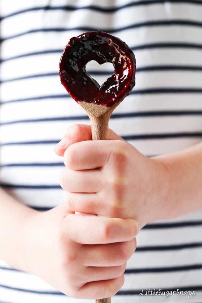 Fruit sauce on a spoon being held by a child.