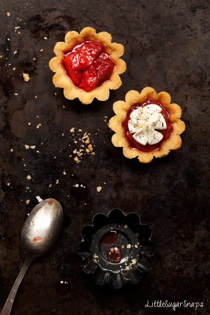 Two small Strawberry tarts - one is topped with piped cream.