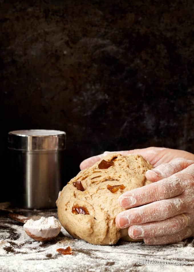 Person kneading dates into bread dough.