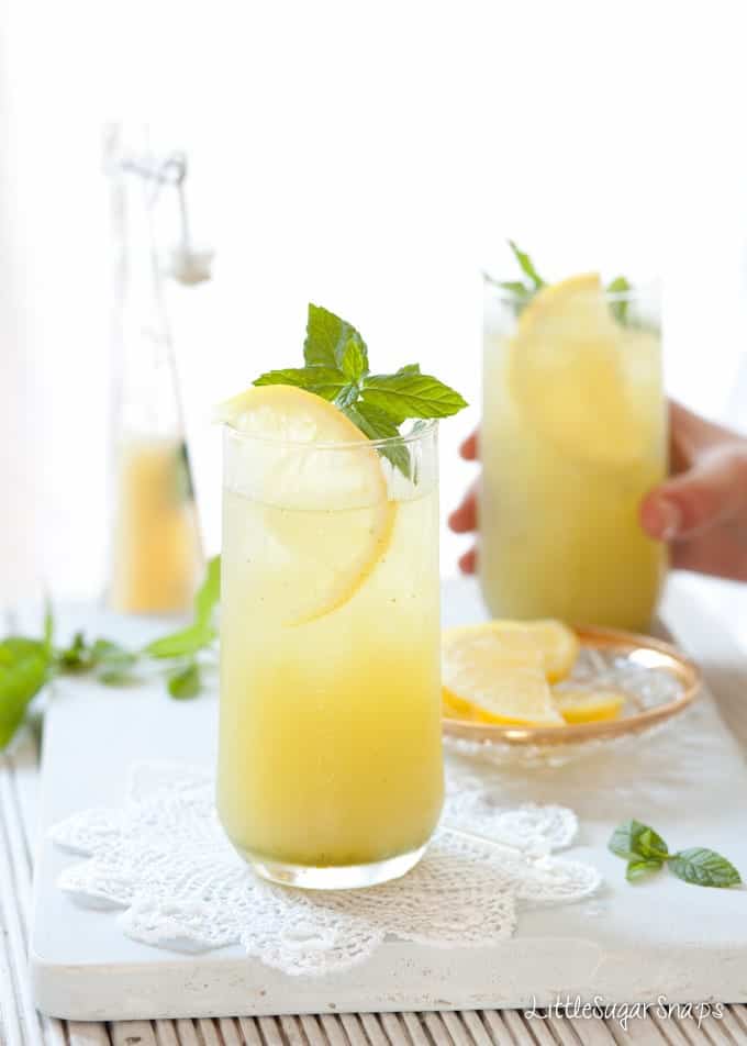 Person taking a glass of apple juice with lemon and mint.