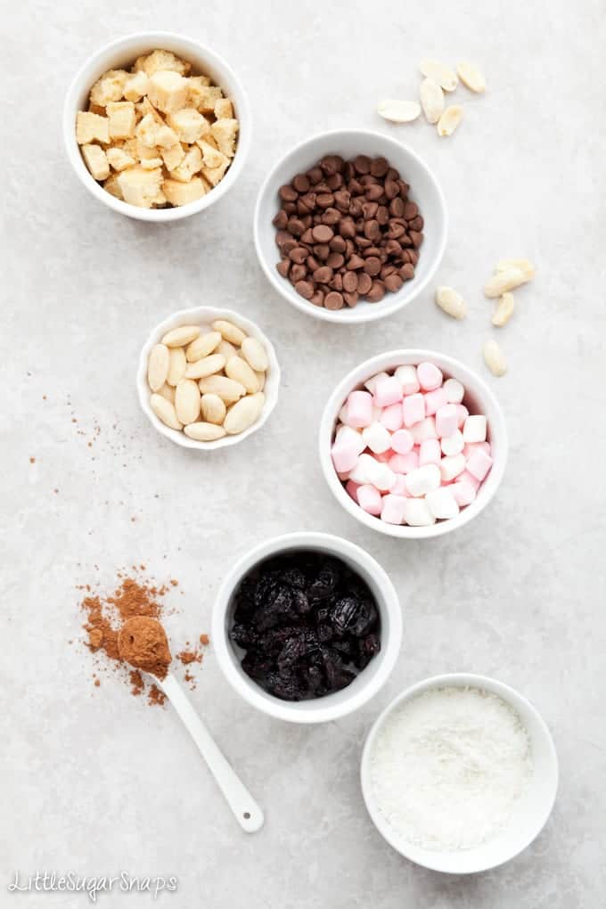 Baking ingredients in bowls - chocolate chips, cookies, nuts, dried fruit, marshmallow & coconut
