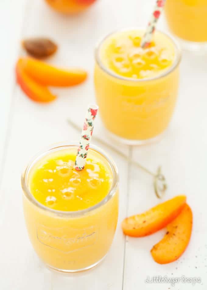 Yellow smoothies in small glasses with floral print paper straws