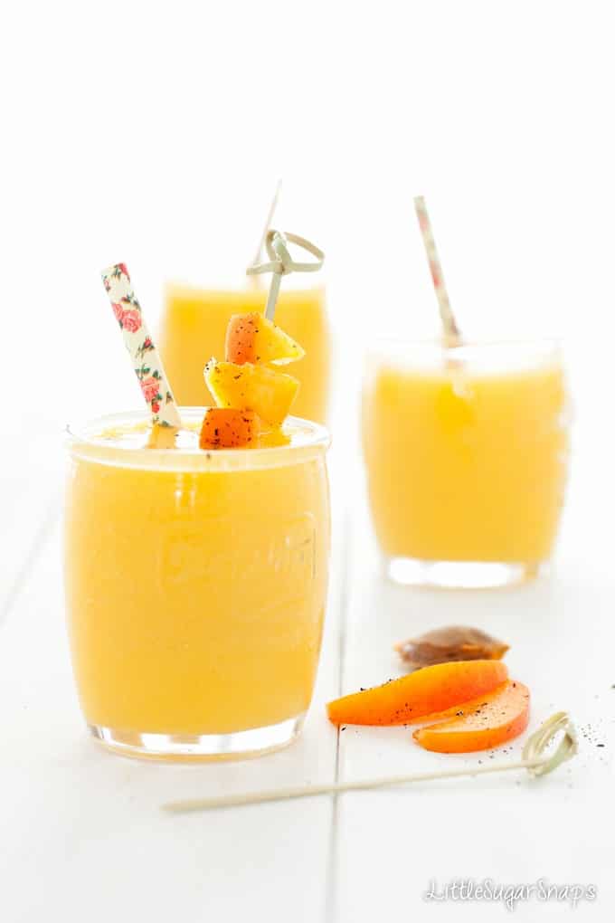 Yellow mango smoothie with apricot garnish and a paper straw