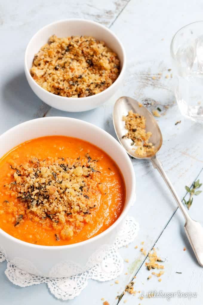 A bowl of creamy tomato soup topped with herb breadcrumbs