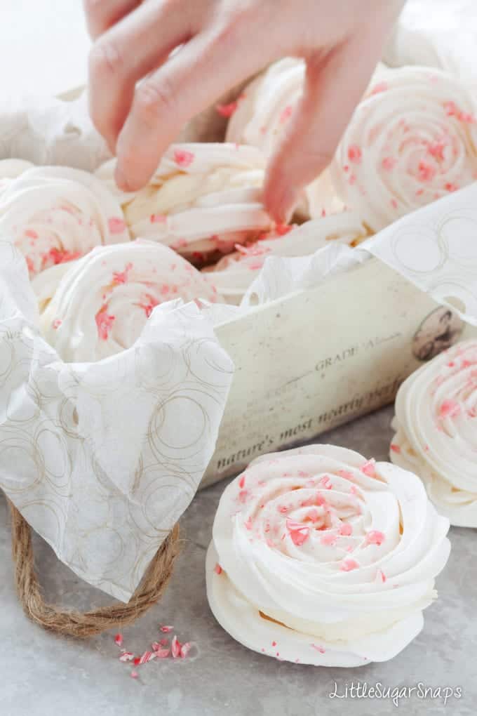 Person taking a Meringue Sandwich topped with candy cane pieces from a box