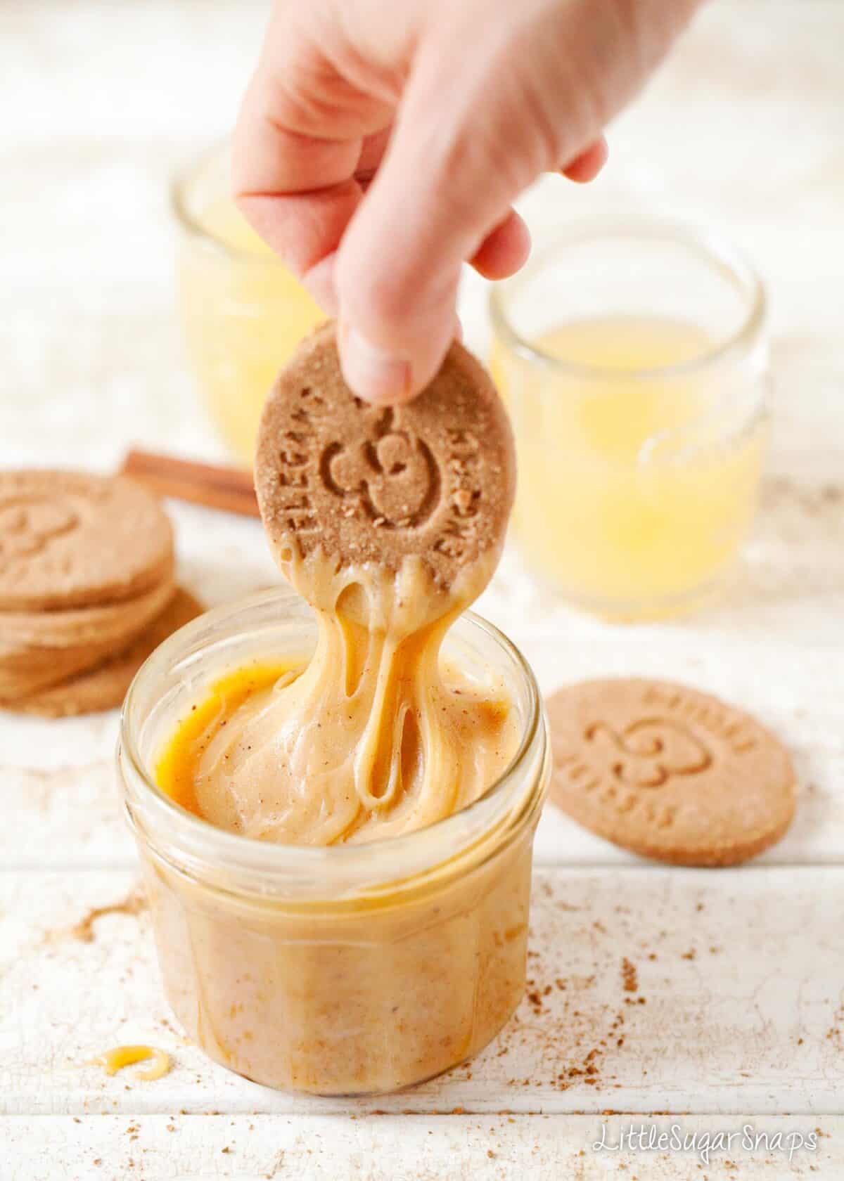 Person dipping cookies into a jar of cinnamon caramel