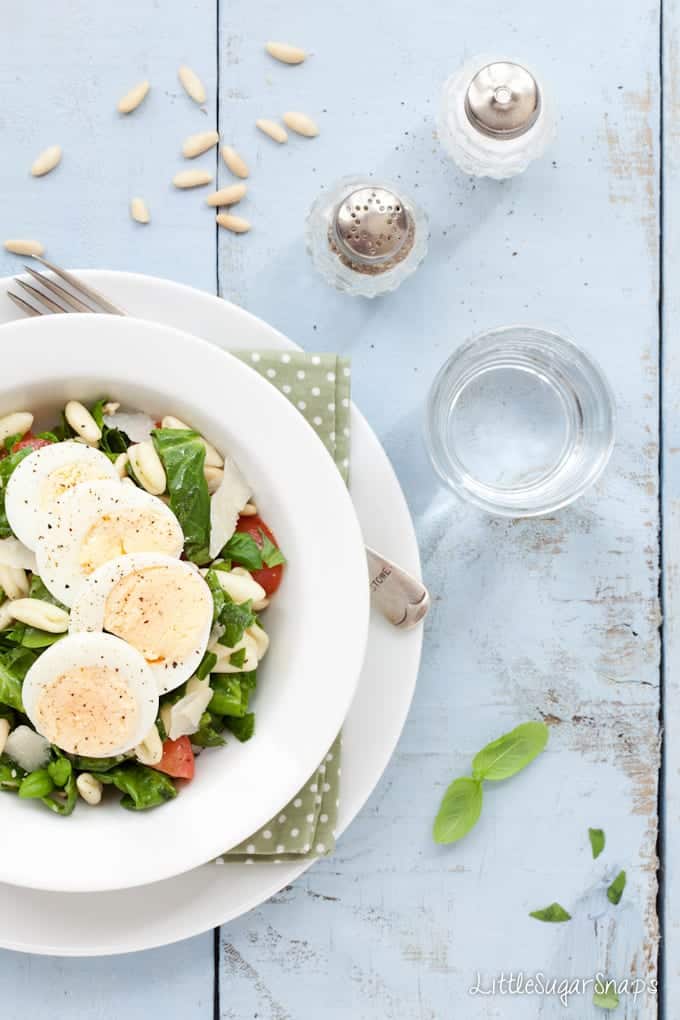 Bowl of pasta, spinach & tomato salad with sliced egg