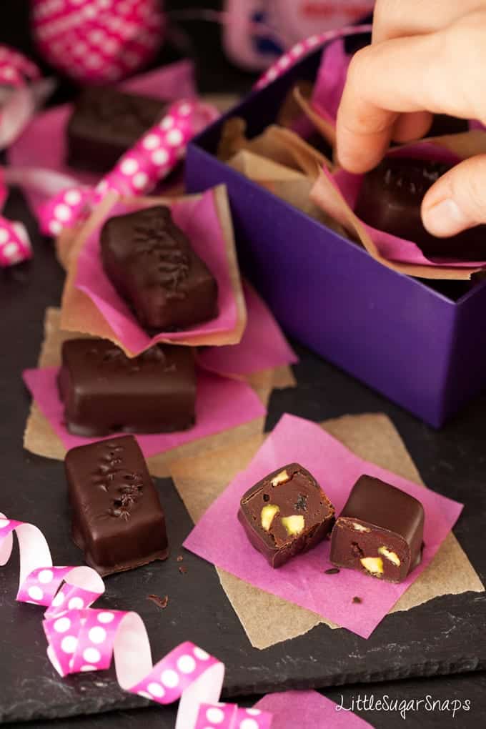 Person taking a caramel chocolate truffle from a gift box