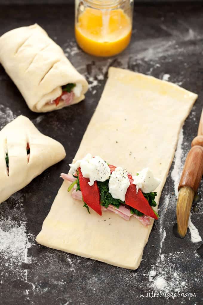 Pastry sheet being topped with spinach, ham and mozzarella cheese