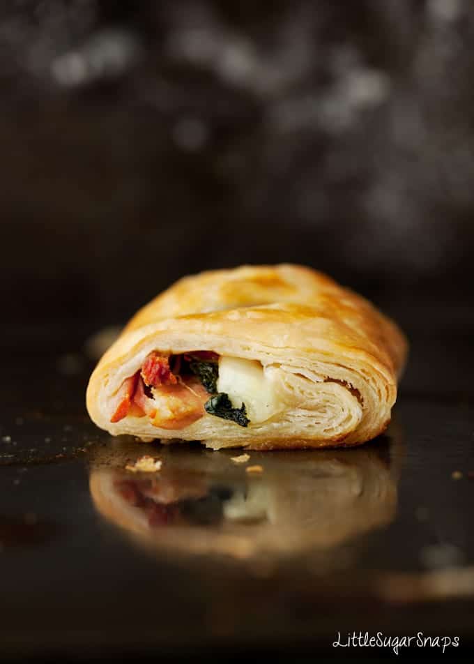 Savoury roll with spinach and ham on a greased baking sheet